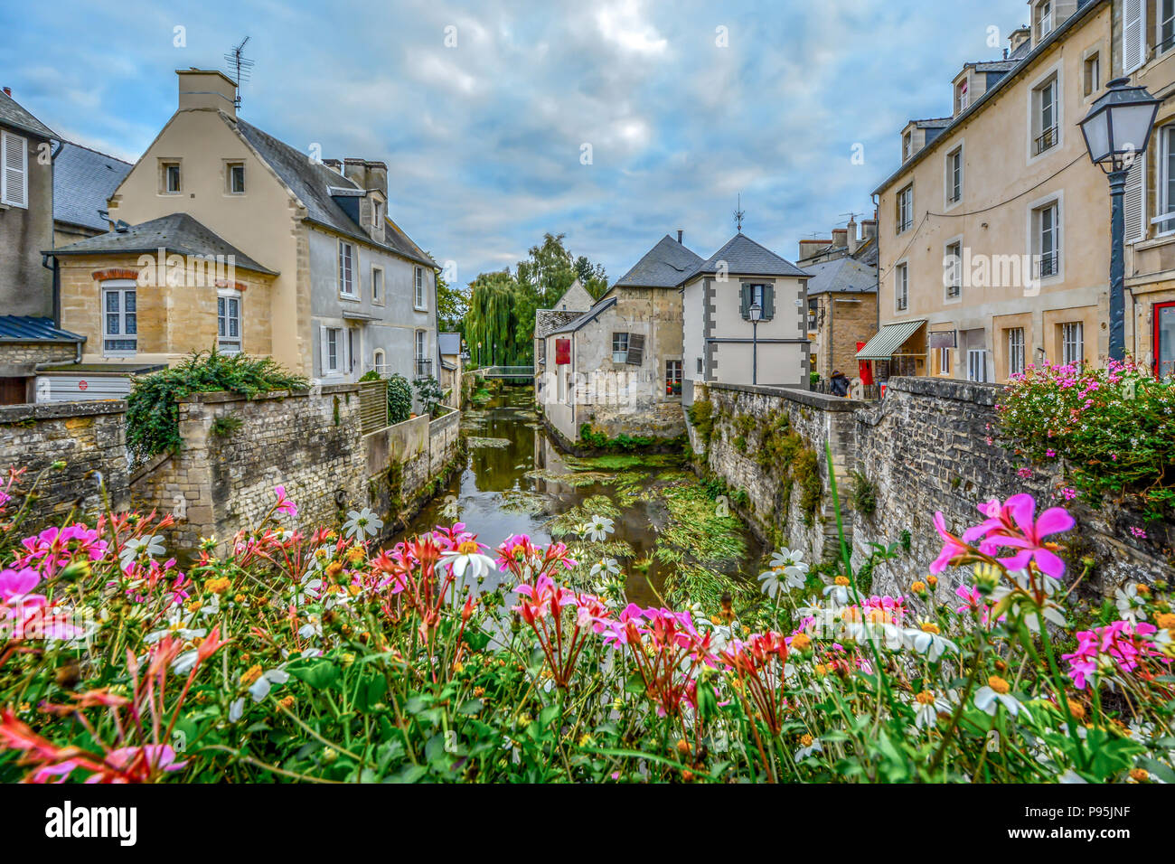 La pittoresca cittadina francese di Bayeux Francia vicino alla costa della Normandia con le case medievali che si affaccia sul fiume Aure su un nuvoloso giorno Foto Stock