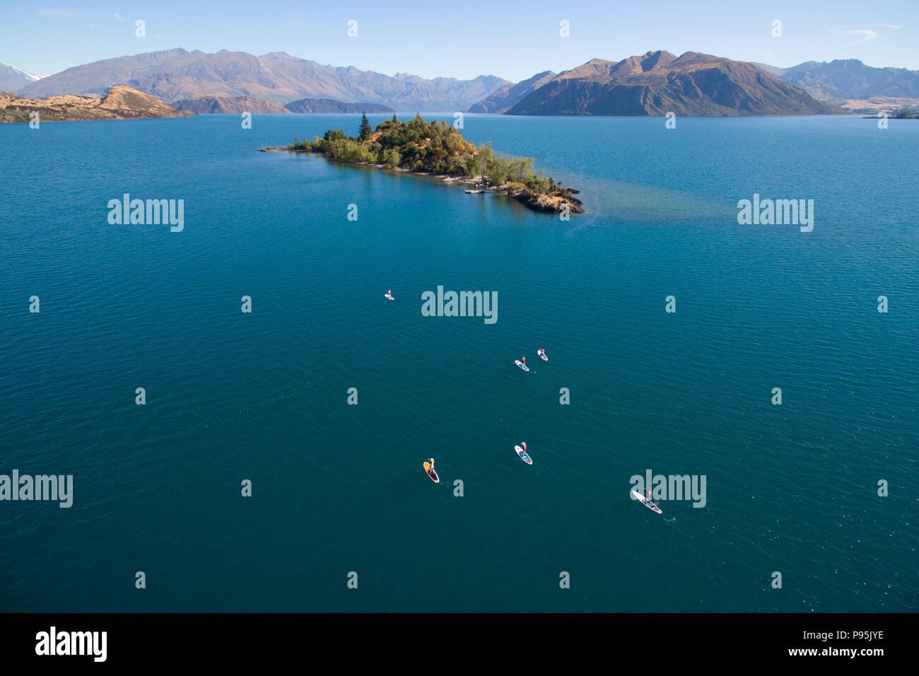 Antenna di stand up paddle boarders paddling a Ruby isola sul lago Wanaka, Nuova Zelanda Foto Stock