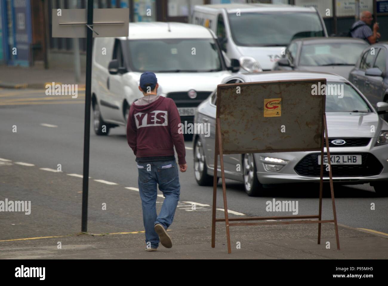 Il grintoso strada urbana shot del maschio bianco ragazzo adolescente con sì t shirt hooded felpa felpa con cappuccio visto da dietro Foto Stock