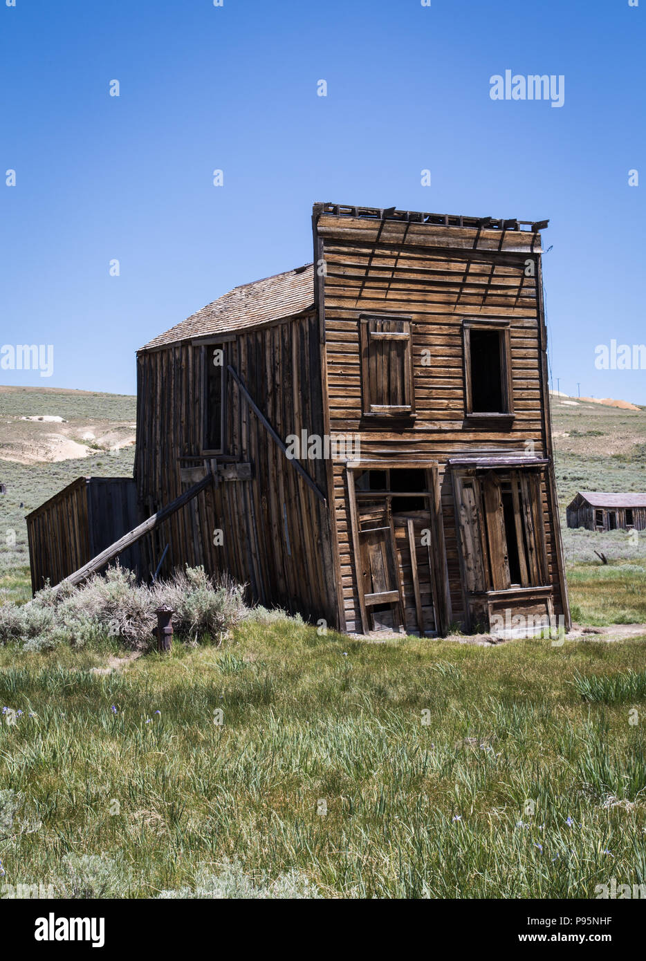 Un vecchio hotel si appoggia al lato in abbandonato il vecchio West Town di Bodie, California, che ora è conservato il parco dello stato. Foto Stock