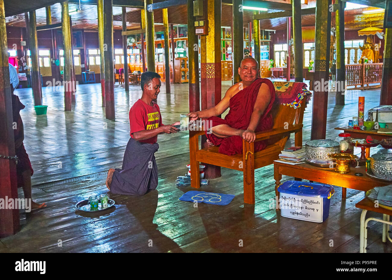 YWAMA, MYANMAR - 18 febbraio 2018: Il sorridente Bhikkhu (monaco buddista) bevande limonata in sala da preghiera di Nga Phe Chaung Monastero di jumping gatti, o Foto Stock