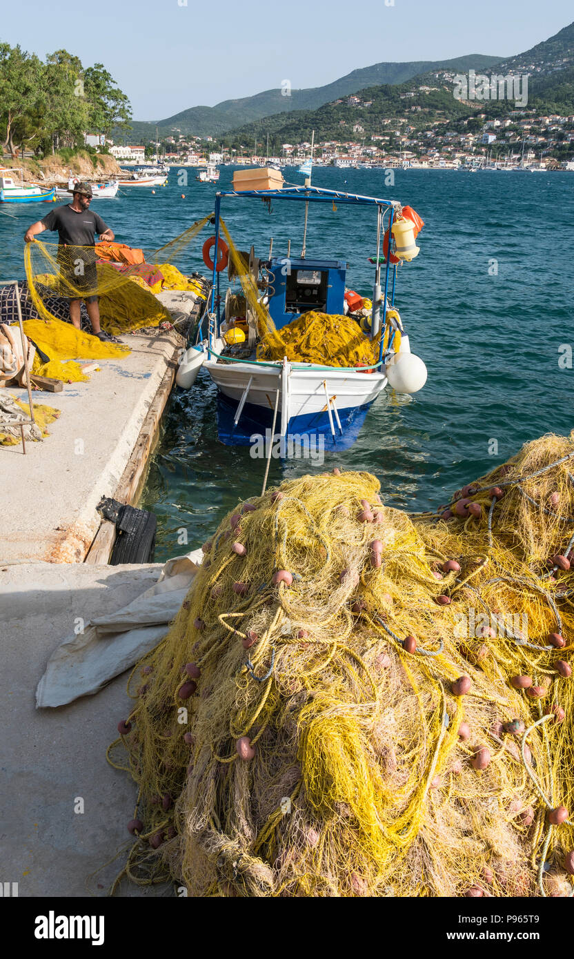 Fisherman e reti da pesca sul porto nord quay a Vathy del porto con la città di Vathi in background. Sull'isola di Ithaca, Mar Ionio, G Foto Stock