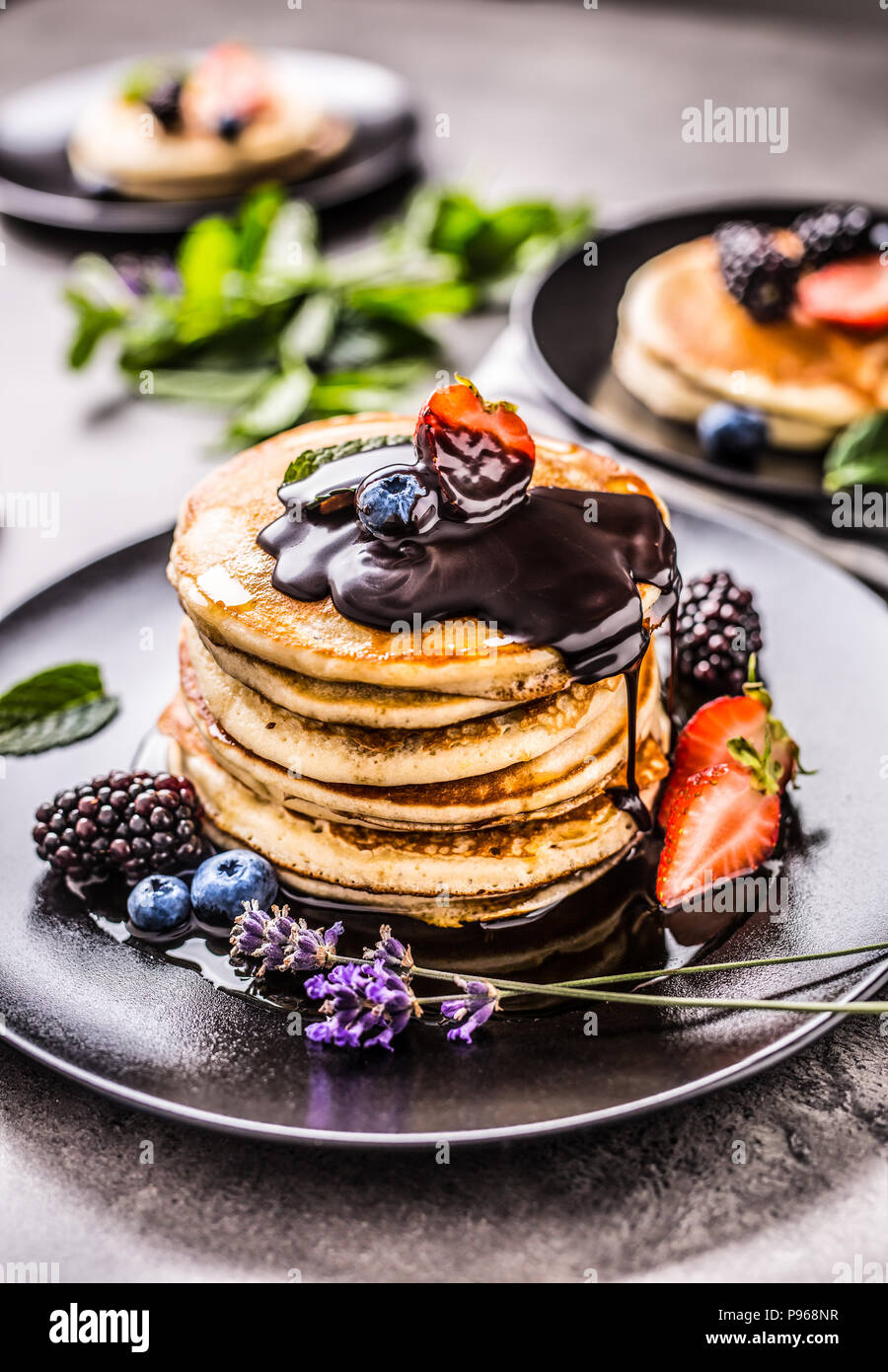 Pancake con fragole mirtilli more di lavanda con foglie di menta e cioccolata calda. Foto Stock