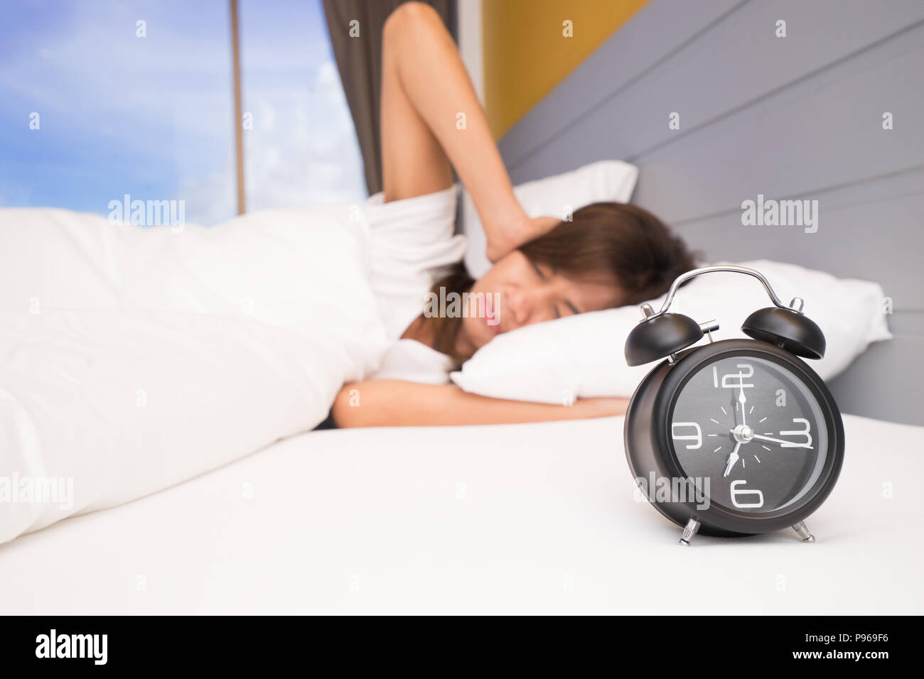 Wake up, donna asiatica nel letto che si estende la mano per sveglia. ragazza si spegne la sveglia svegliarsi al mattino. Giovane donna addormentata e allarme clo Foto Stock