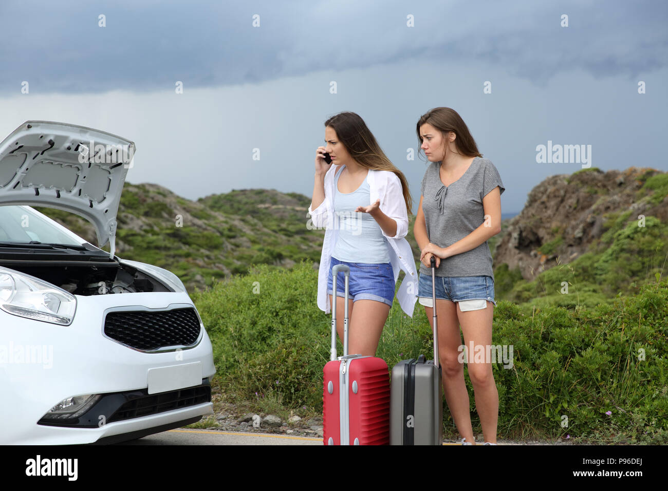 Due turisti arrabbiato sostenendo sul telefono dopo la ripartizione auto guardando a cofano aperto Foto Stock