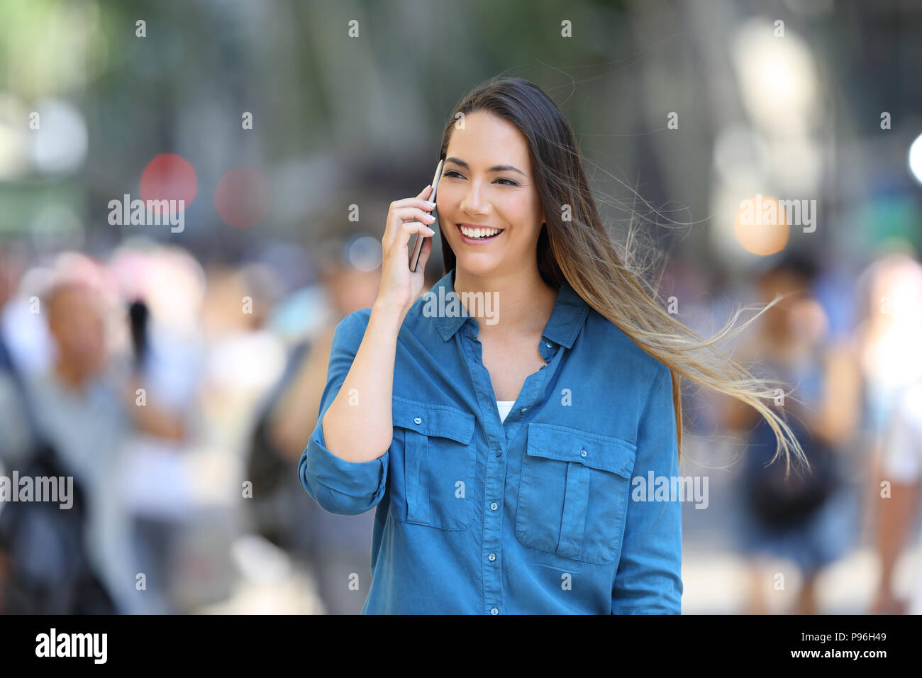 Donna felice in blu parla al telefono di camminare sulla strada Foto Stock