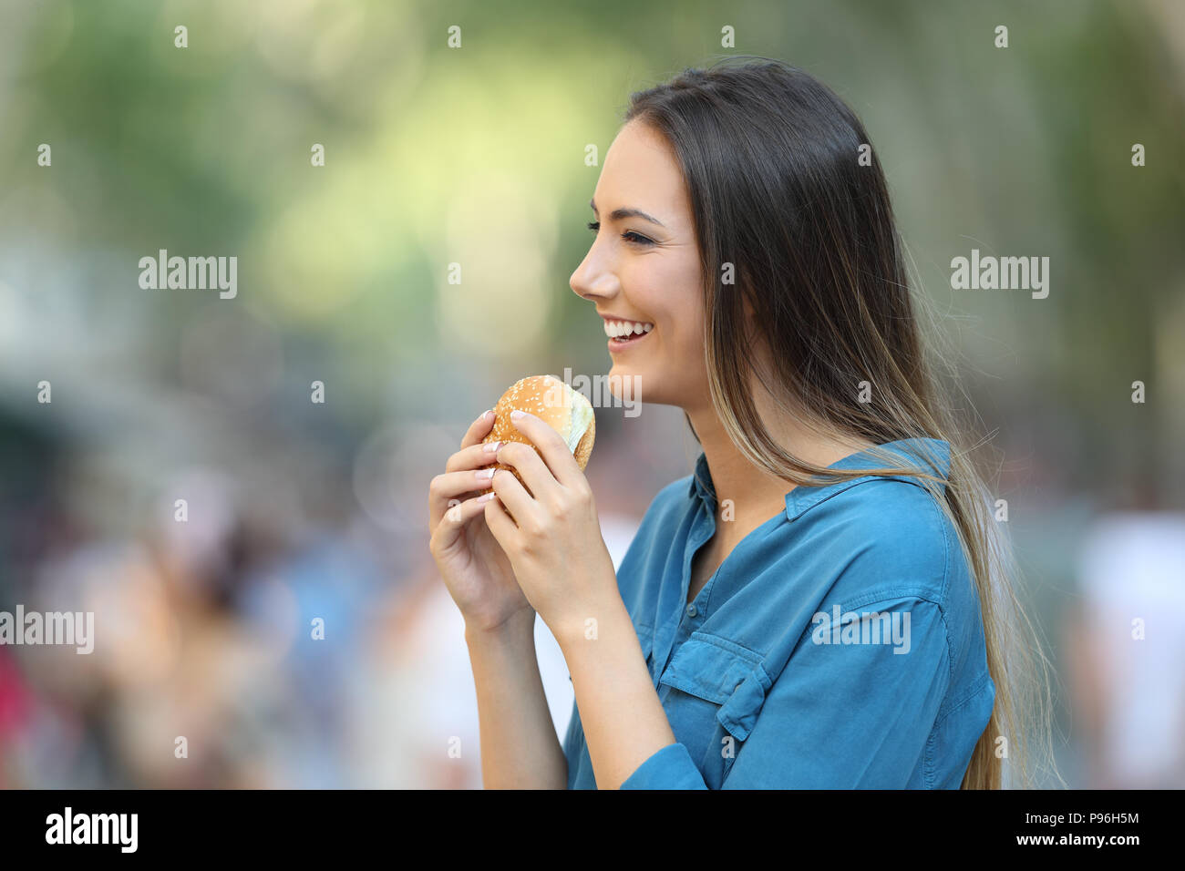Profilo di una donna tenendo un burger sulla strada Foto Stock