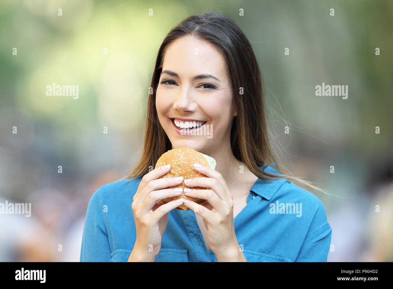 Vista frontale il ritratto di una donna tenendo un burger guardando la fotocamera Foto Stock