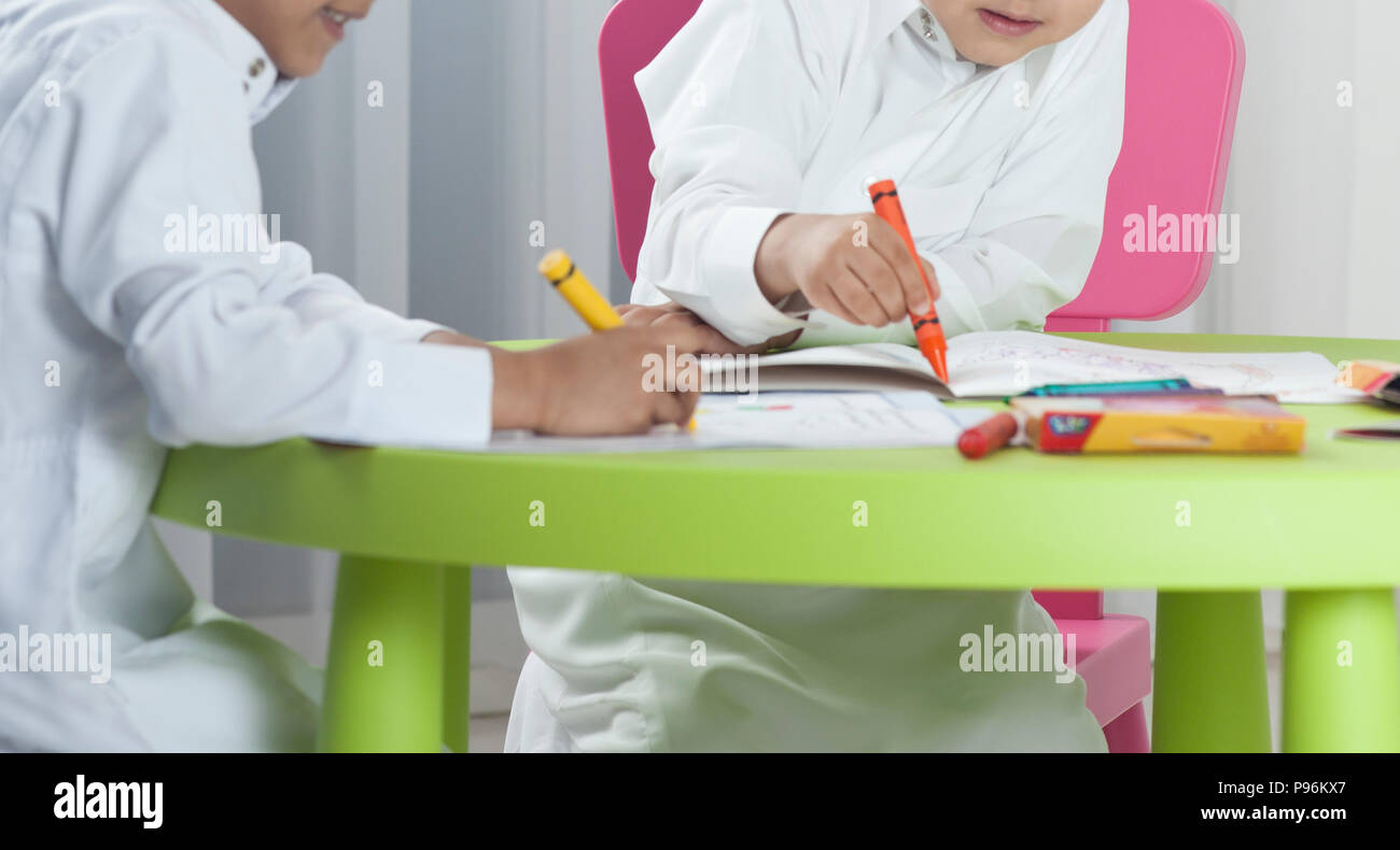 I ragazzi di disegno con le matite colorate su carta in una tabella Foto Stock