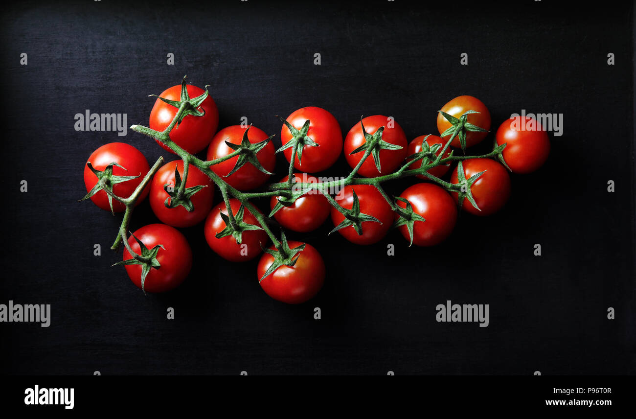 Grappolo di pomodori su sfondo scuro. Foto Stock