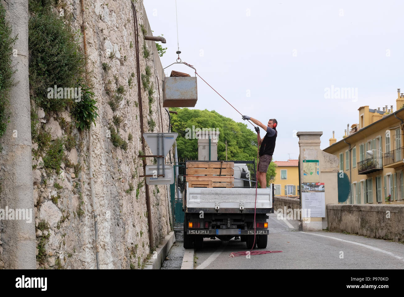 Nizza, Francia. Workman in piedi sul camion utilizzando una puleggia per il trasferimento di carico su parete alta Foto Stock