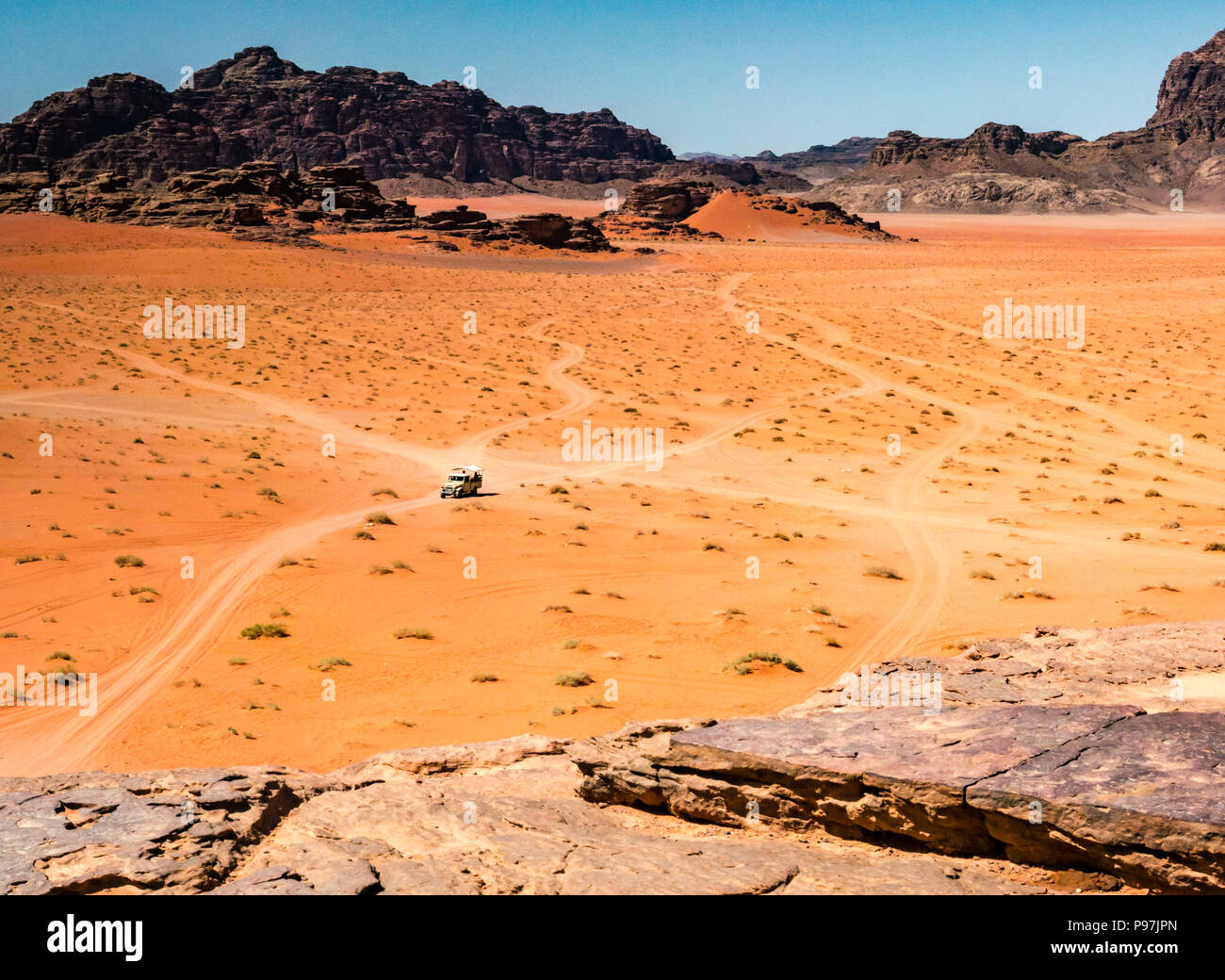 Veicolo 4x4 e tracce nel vasto desolata distesa di Wadi Rum vallata desertica con montagne, Giordania, Medio Oriente Foto Stock
