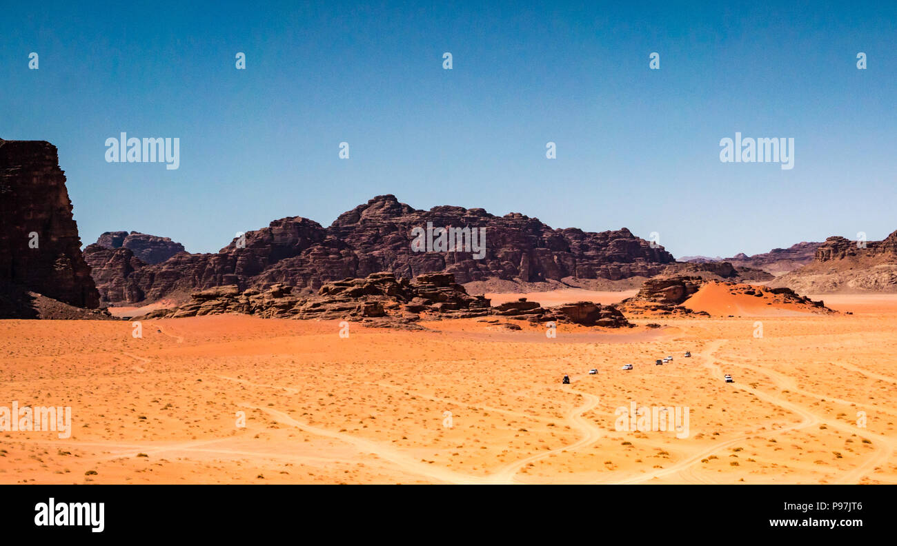Convoglio di veicoli 4x4 e tracce nella desolata distesa di Wadi Rum vallata desertica con montagne, Giordania, Medio Oriente Foto Stock