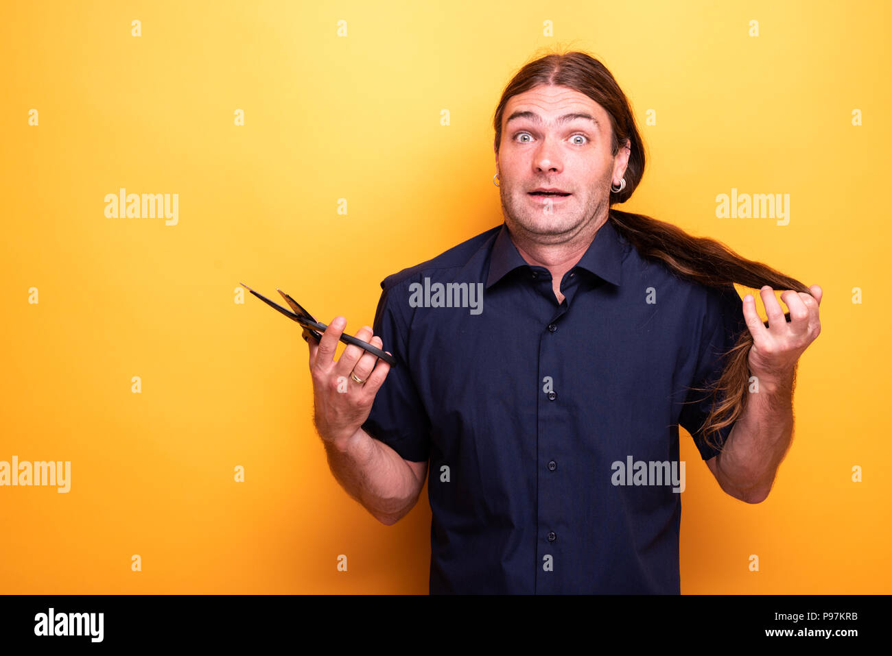 Uomo con sguardo disperato pensando di tagliare i peli con le forbici Foto Stock