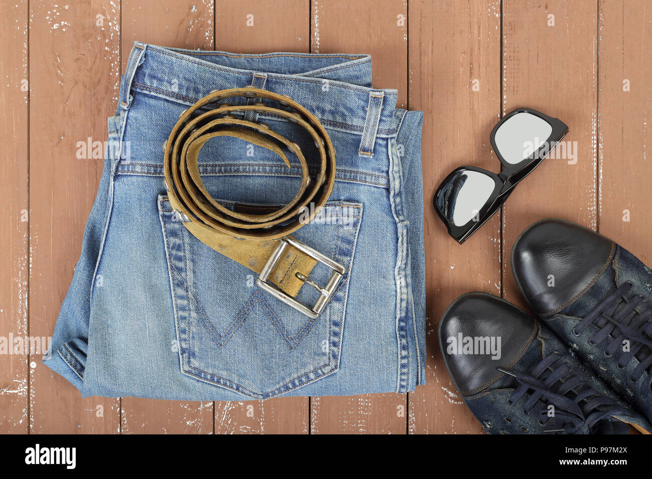Abbigliamento, calzature e accessori - vista superiore occhiali da sole,  cinghia in pelle, scarpe e jeans blu su uno sfondo di legno Foto stock -  Alamy
