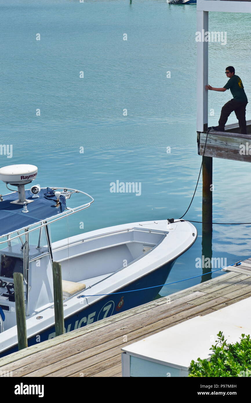 Local Marsh Harbour, Bahamas poliziotto in piedi sopra la barca di polizia il trasporto su acqua. Foto Stock