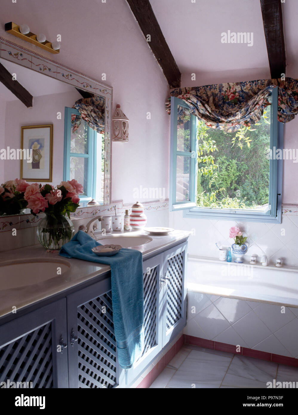 Vaso di rose rosa sul mobiletto bagno con lavandini doppi e blu traforature porte nel paese spagnolo bagno Foto Stock