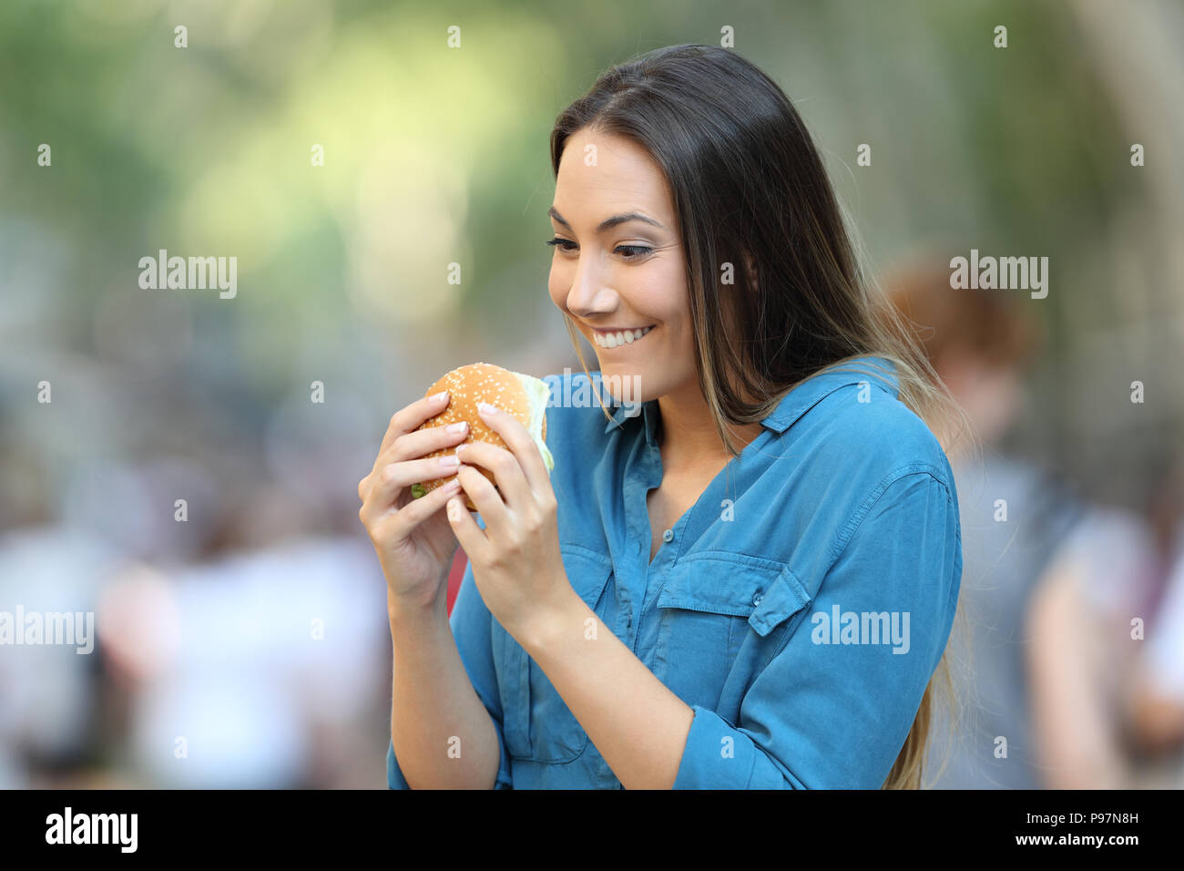 Excited donna pronto a mangiare un hamburger sulla strada Foto Stock