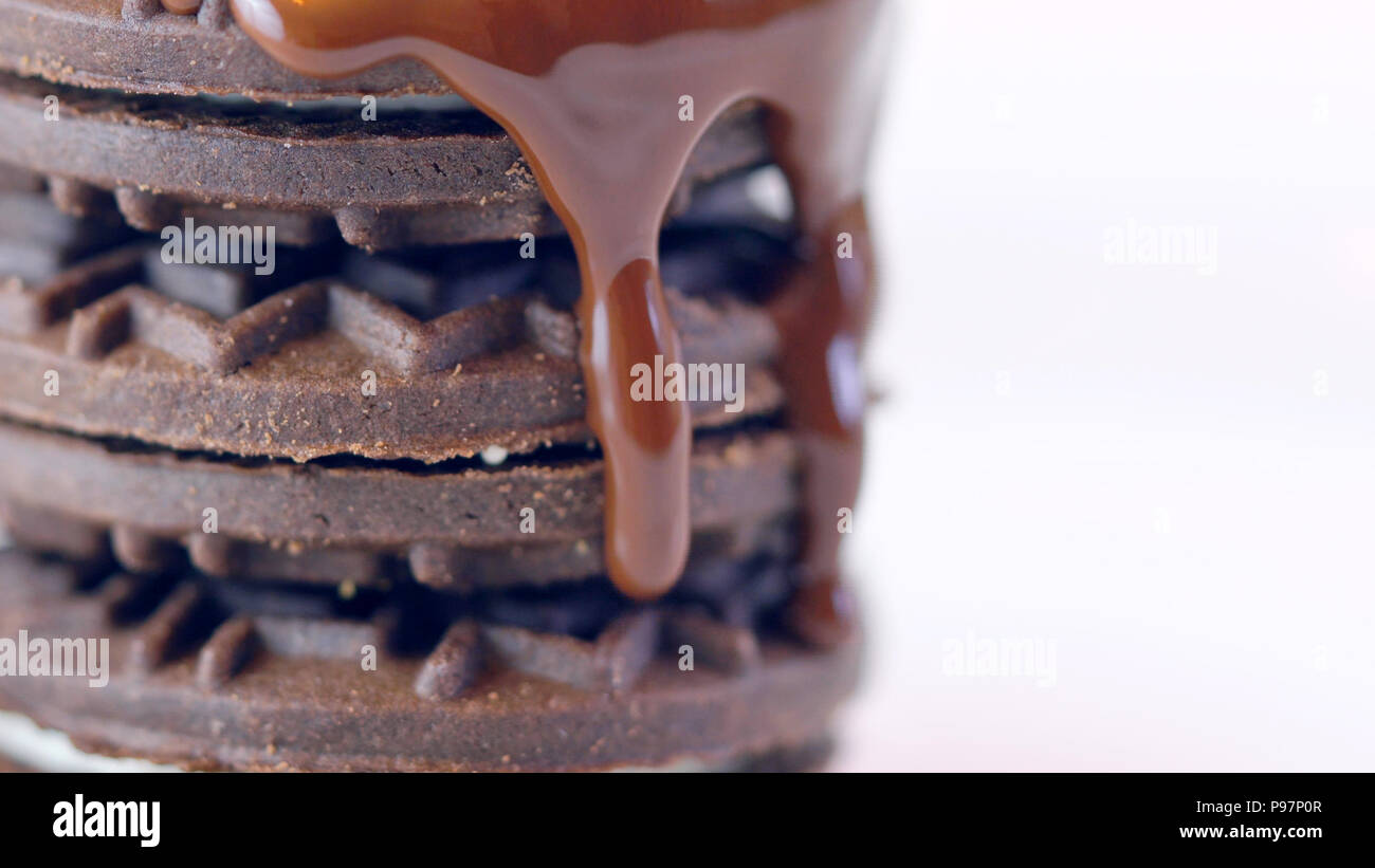 Salsa al cioccolato gocciolamento sulla pila di biscotti, macro closeup. Foto Stock