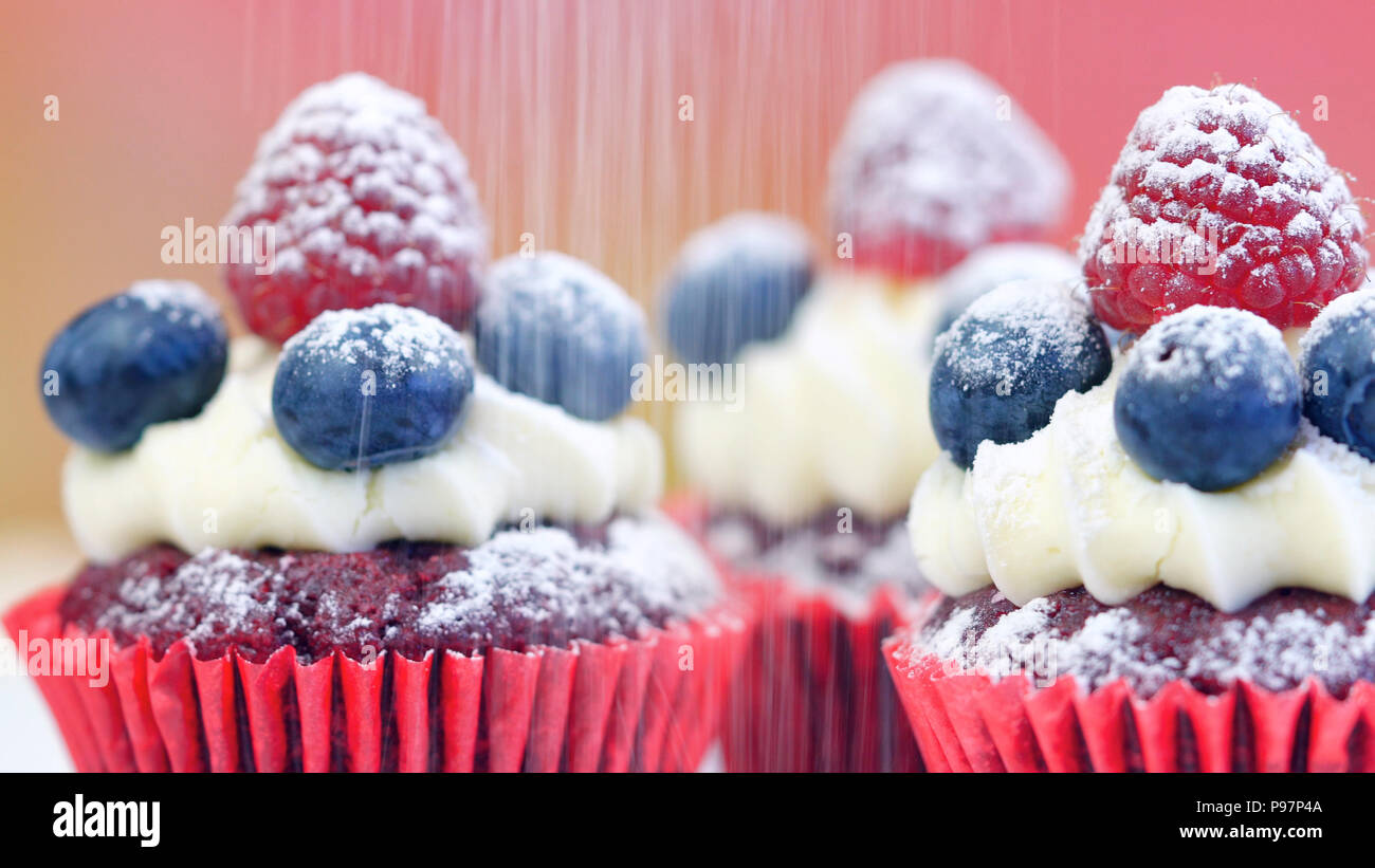Macro closeup di velluto rosso tortine decorate con frutta e spolverata con zucchero prodotti dolciari. Foto Stock