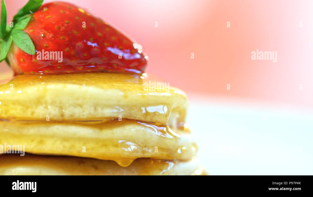 Pila di pancake con fragole sulla parte superiore e una spruzzata di sciroppo, macro closeup. Foto Stock
