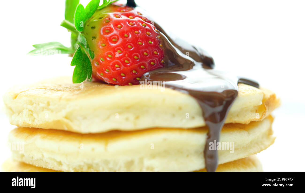 Pila di pancake con fragole e spruzzata con salsa di cioccolato, macro closeup. Foto Stock