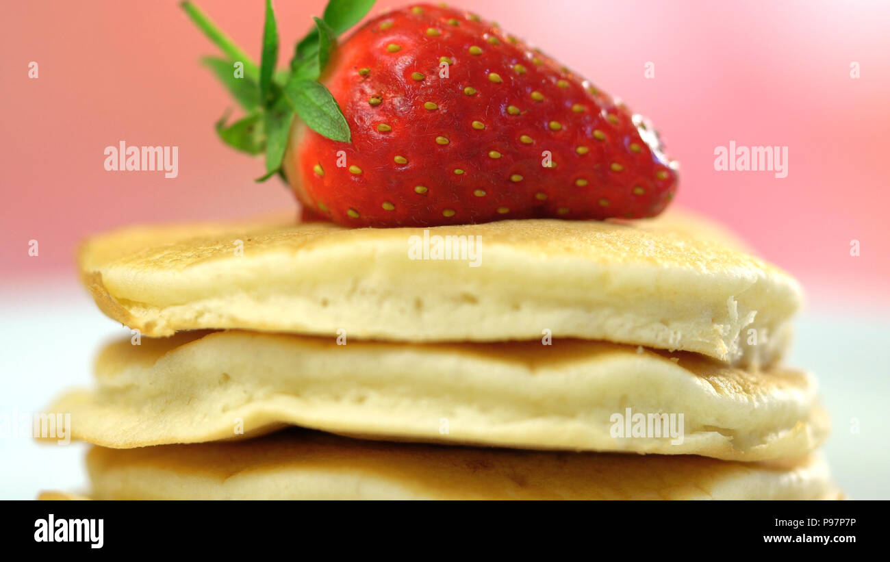 Pila di pancake con fragole in cima, macro closeup. Foto Stock