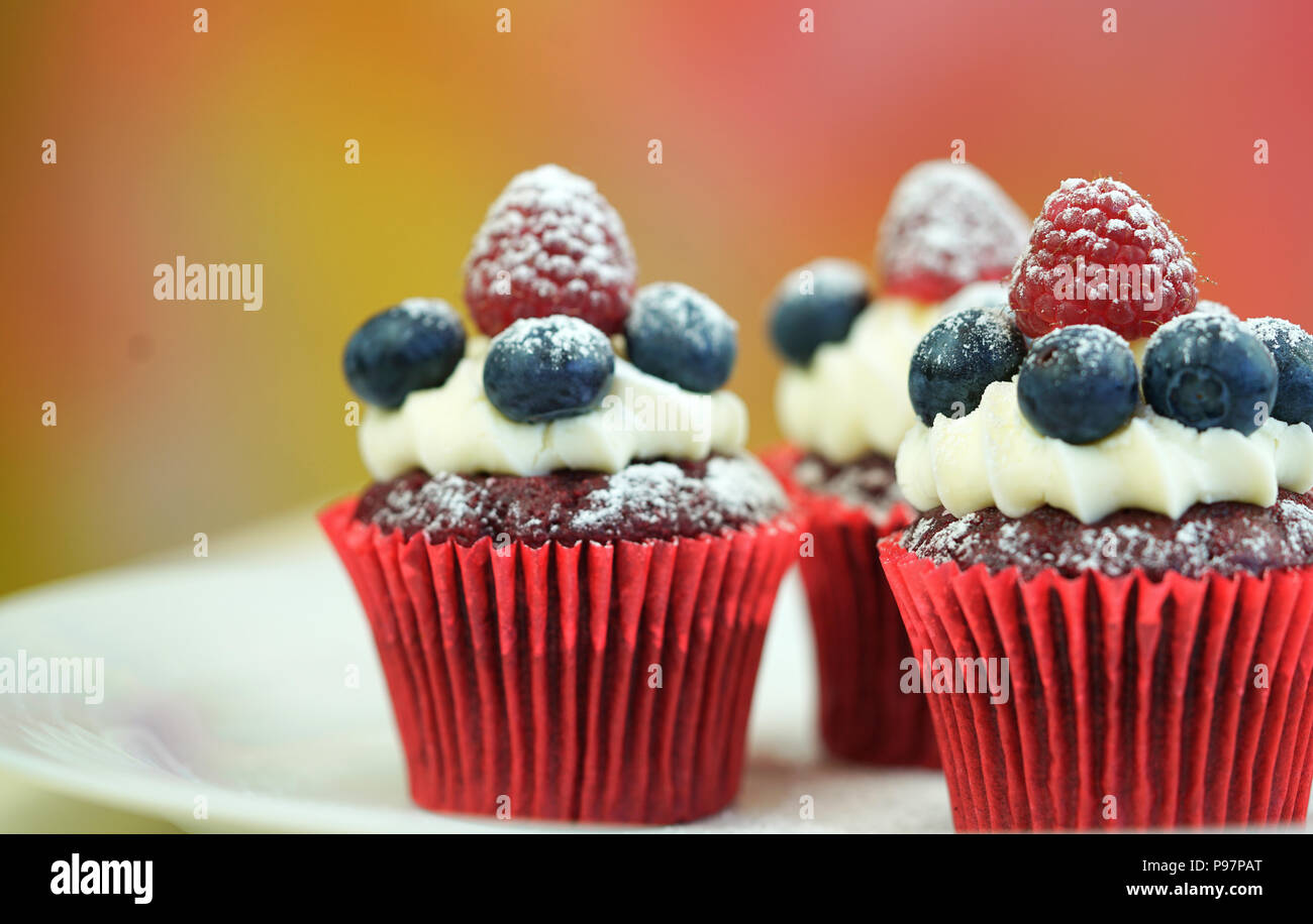 Macro closeup di velluto rosso tortine decorate con frutta e spolverata con zucchero prodotti dolciari. Foto Stock