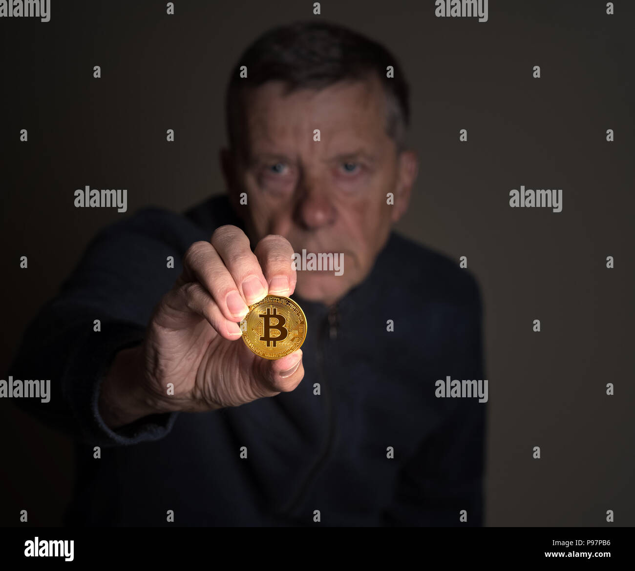 Senior man tenendo un bitcoin per la lunghezza del braccio Foto Stock
