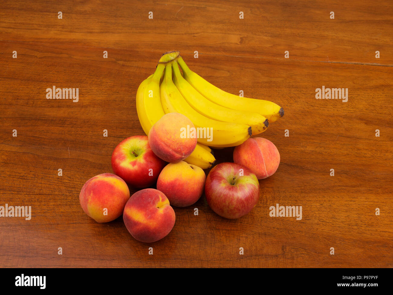 Banane per le pesche e le mele su una tavola di legno Foto Stock