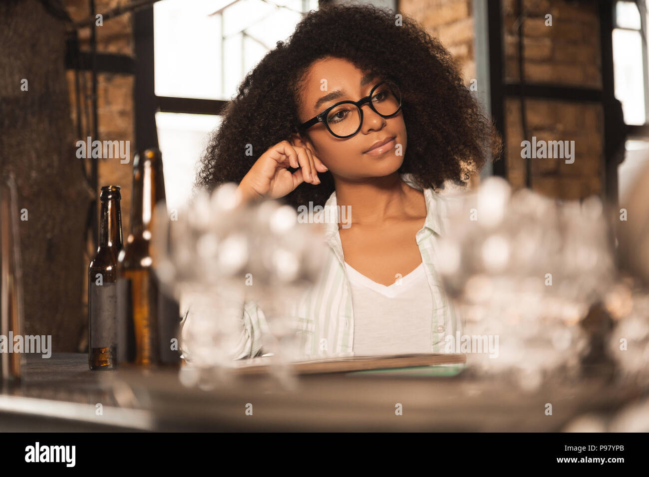 Curly giovane donna ascoltando qualcuno al pub Foto Stock