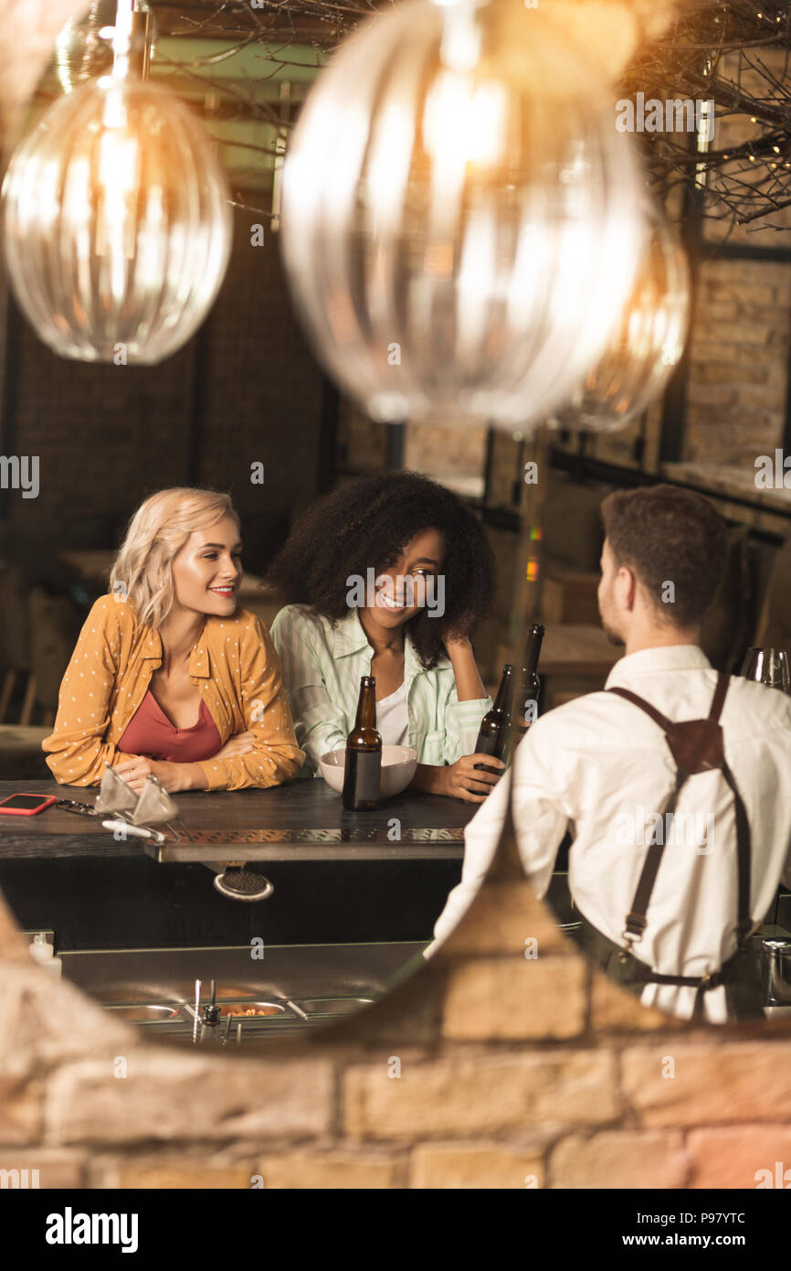 Upbeat giovani donne a parlare al barman Foto Stock