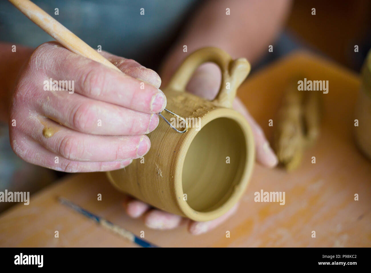 Professional potter rendendo modello sulla tazza di argilla con un attrezzo speciale in ceramica Foto Stock