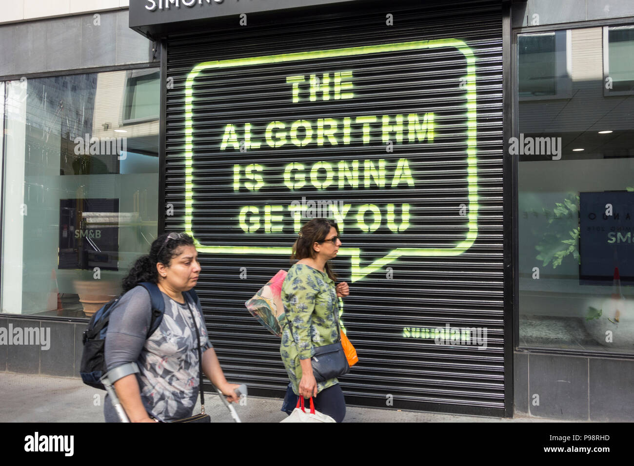 Le persone che passano oltre l'algoritmo è gonna vi otterrà da Subdude, di fronte a Rathbone Square HQ di Facebook, a Londra, Inghilterra, Regno Unito Foto Stock