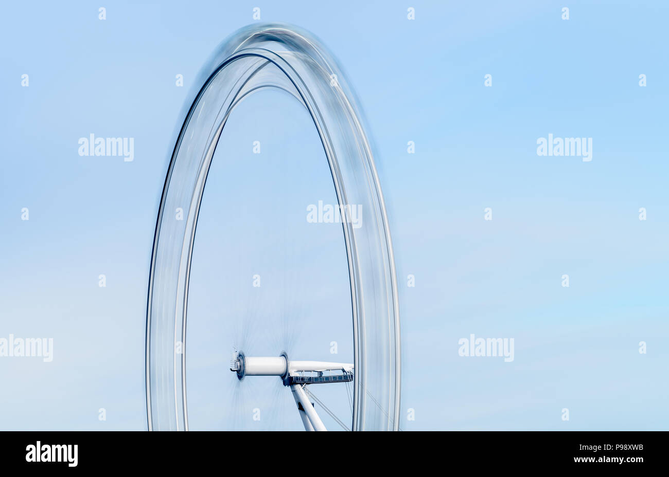 Una lunga esposizione vista della metà superiore del London Eye ruota panoramica sulla South Bank di Londra che figurano a girare rapidamente contro un cielo blu Foto Stock