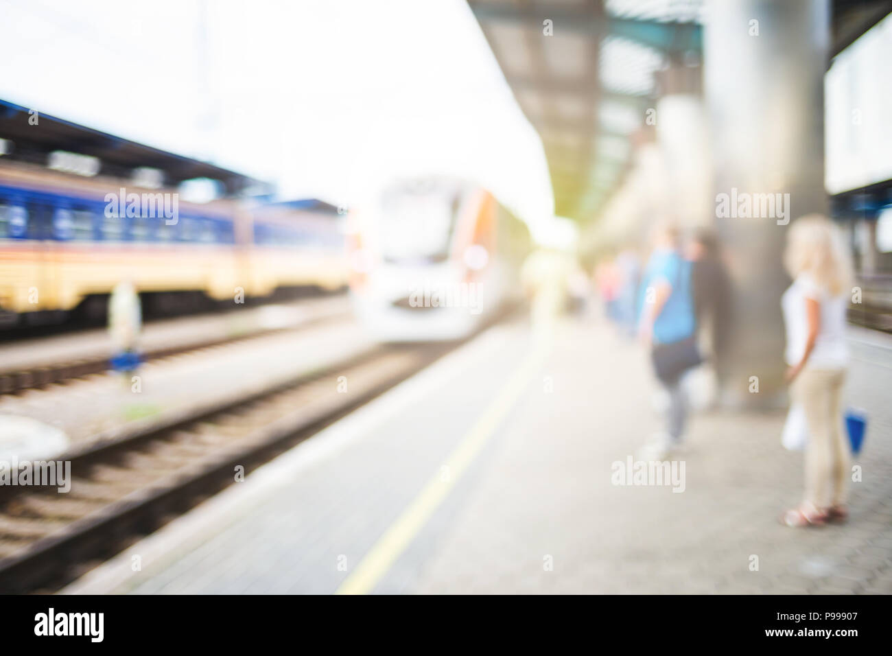 Immagine sfocata con i passeggeri in attesa di treno sulla platfom presso la stazione ferroviaria. I turisti con il bagaglio. Foto Stock