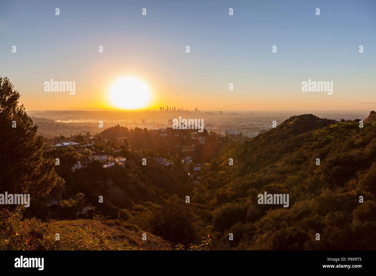 Smoggy orange sunrise vista da Runyon Canyon Park verso Hollywood e Los Angeles, California. Foto Stock