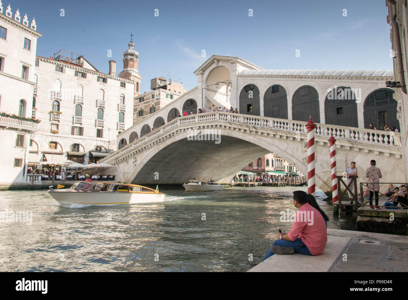 L'Europa, Italia, Veneto, Venezia. Le persone in riposo a riva del fiume Canale Grande (Grand Canal) vicino al Ponte di Rialto) a Venezia. Foto Stock