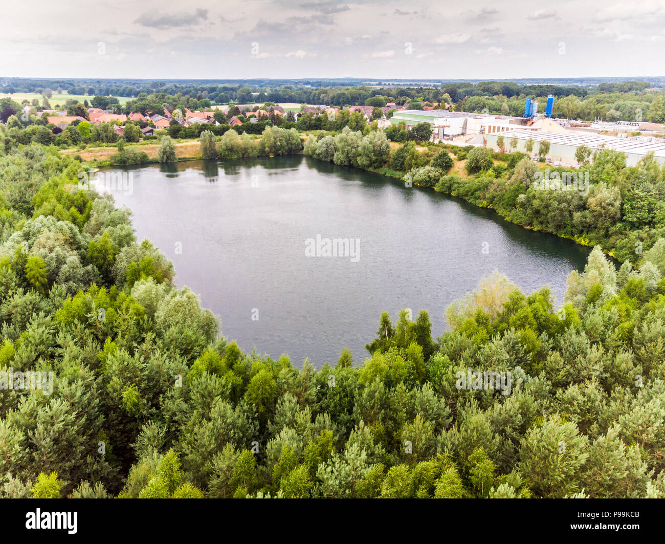 Quasi ad angolo retto, lago foro residuo di un ex cava di sabbia, circondato da una densa popolazione di albero vicino a Gifhorn, Germania Foto Stock