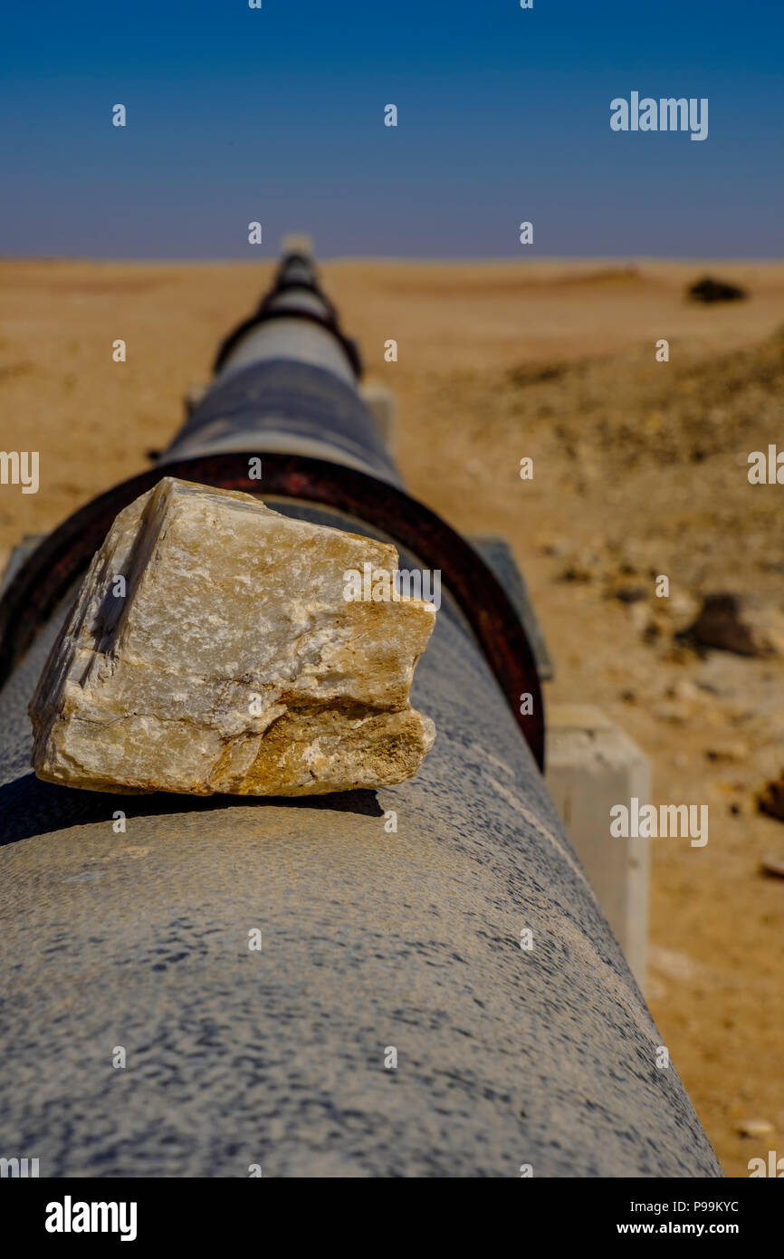 Focus sul pezzo di roccia di silice sul tubo di ferro da stiro orizzonte nel deserto del Namib portando acqua approvvigionamento da impianto di desalinizzazione di Swakopmund a uraniu Foto Stock