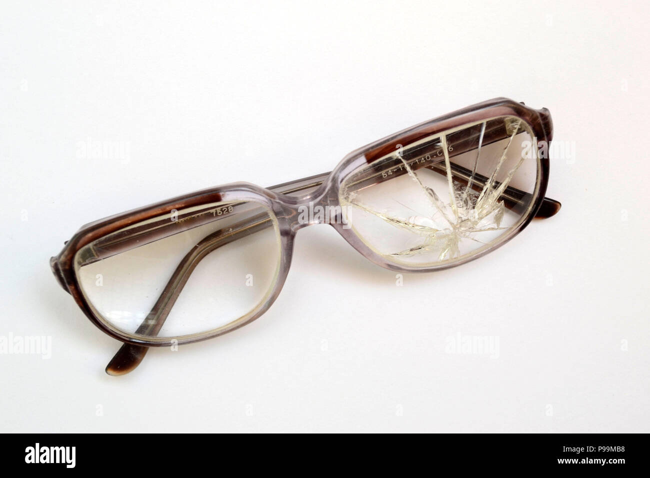 Vecchi occhiali con il vetro rotto su sfondo bianco Foto Stock