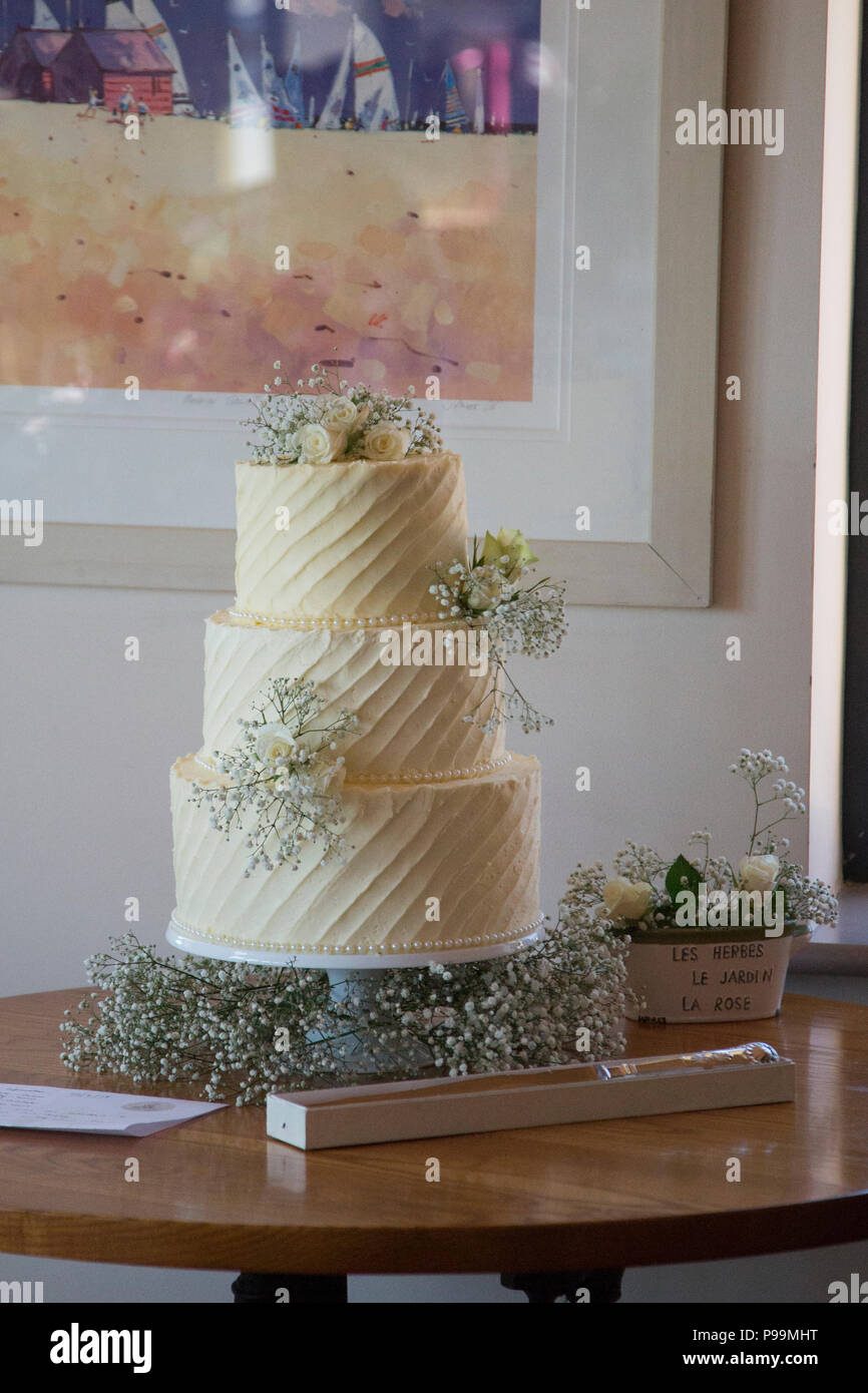 Tre livelli di torta nuziale coperta in glassa di crema di burro e fiori reale Foto Stock