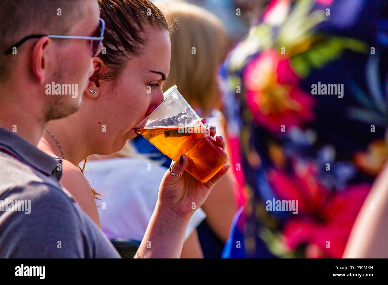 Donna di bere birra da una tazza di plastica in corrispondenza di una all'aperto evento estivo, UK. Maggio 2018. Foto Stock