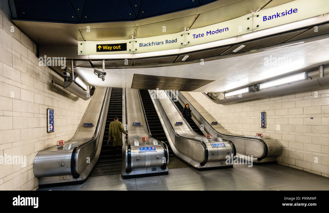 L uomo e la donna pendolari utilizzando Escalator nel tubo di Southwark Station di Londra Foto Stock