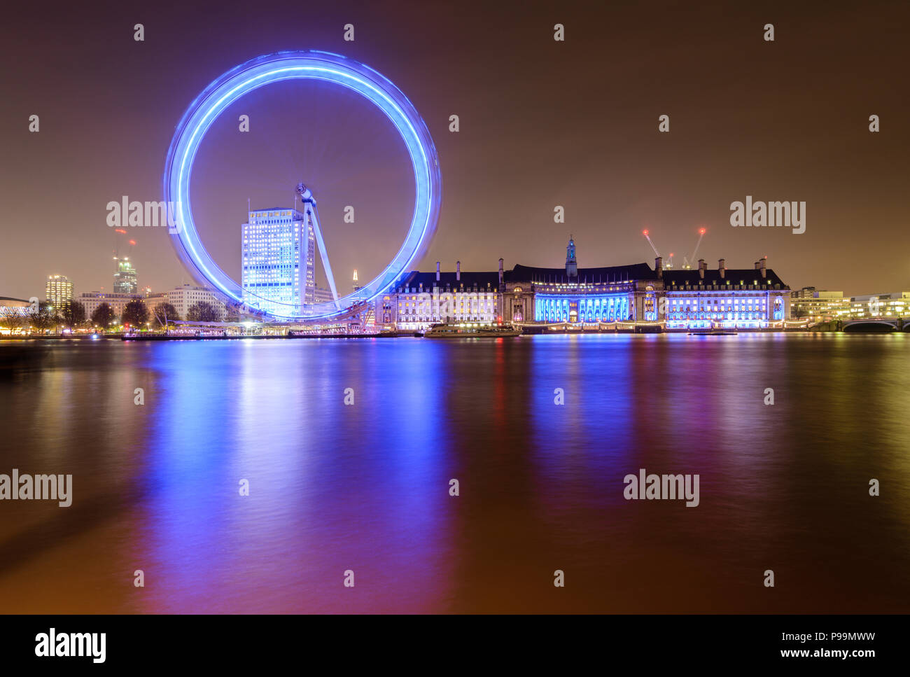 Esposizione lunga notte tempo vista la Coca-Cola London Eye e County Hall da Embankment, Londra, riflesso nel Tamigi, illuminato contro un cielo chiaro Foto Stock