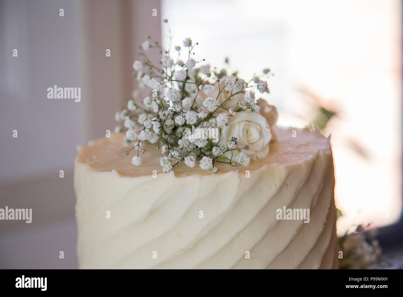 Tre livelli di torta nuziale coperta in glassa di crema di burro e fiori reale Foto Stock
