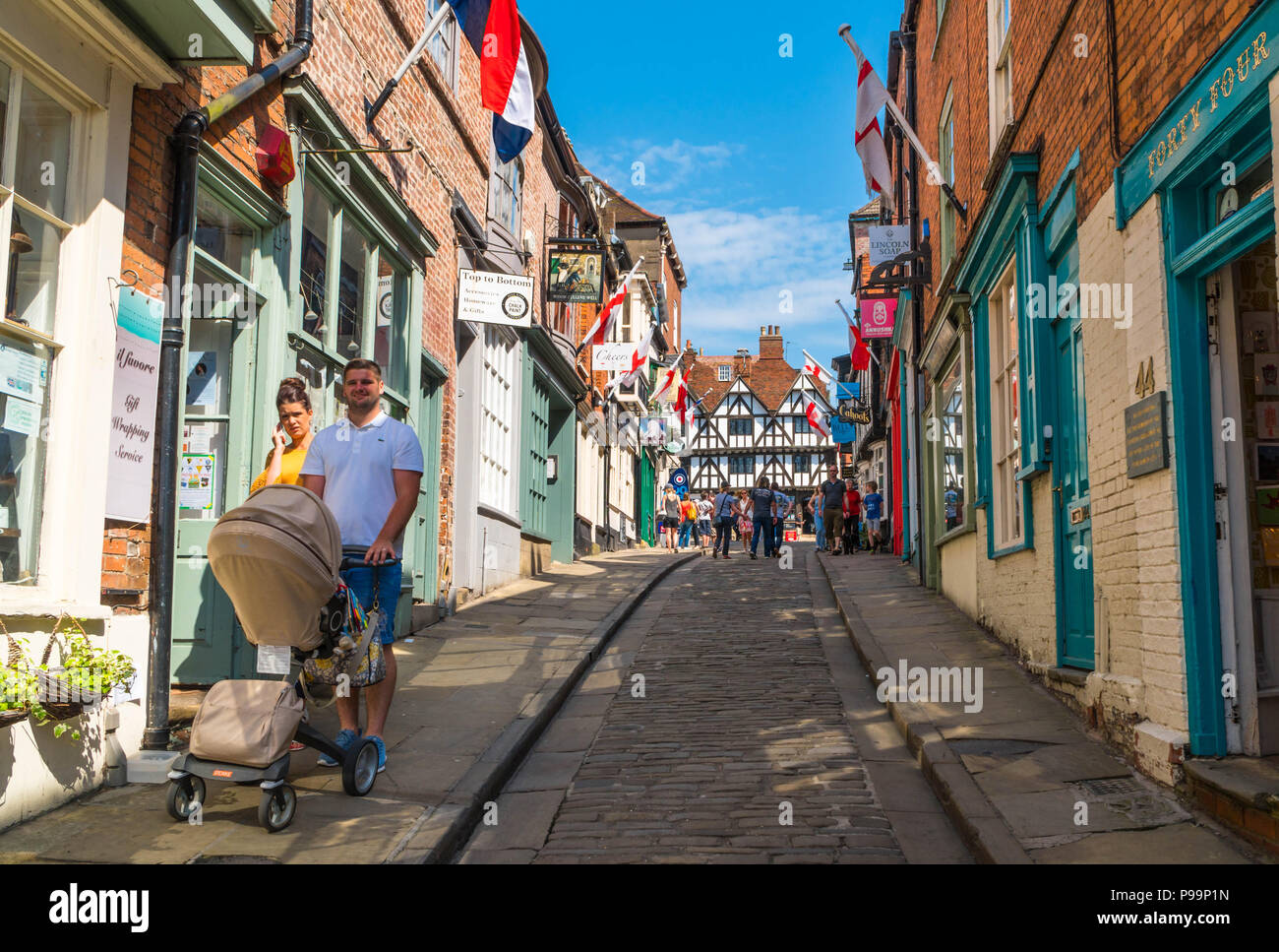 Coppia con passeggino rendendo la loro strada ripida collina Lincoln UK Maggio 2018 Foto Stock