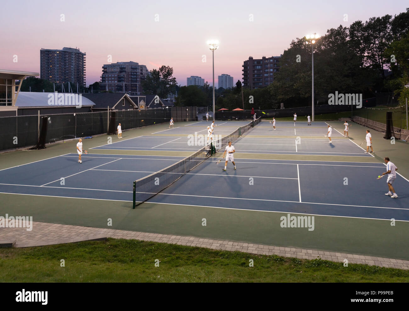 Un gruppo di persone che gioca a tennis al di fuori al crepuscolo in Oakville, Ontario, Canada. Foto Stock