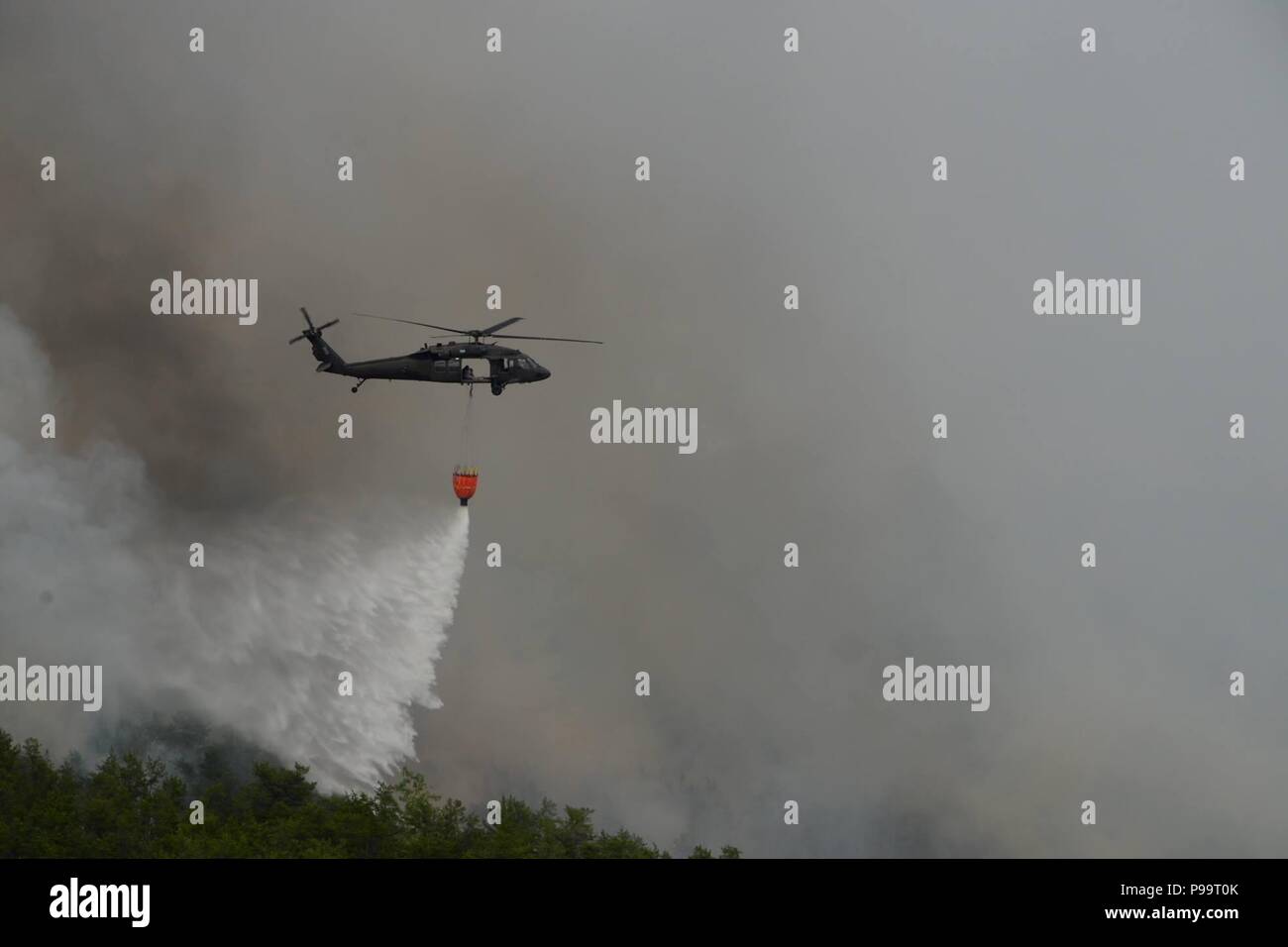 A New York Army National Guard UH-60 assegnati al 3° Battaglione, 142th aviazione, offre 660 galloni di acqua su un incendio di foresta in Flat Rock la foresta di stato in Altona, N.Y. Venerdì 13 Luglio, 2018. Due UH-60 personale di volo ha risposto a un incendio di foresta che scoppiò in Altona, N.Y., e distribuite su cinque centinaia di acri, dal luglio 13-15. Protezione dell'esercito personale di volo volato più missioni a sostegno dei vigili del fuoco del 15 luglio. (N.Y. Esercito nazionale Guard foto di Spc. Andrew Valenza) Foto Stock