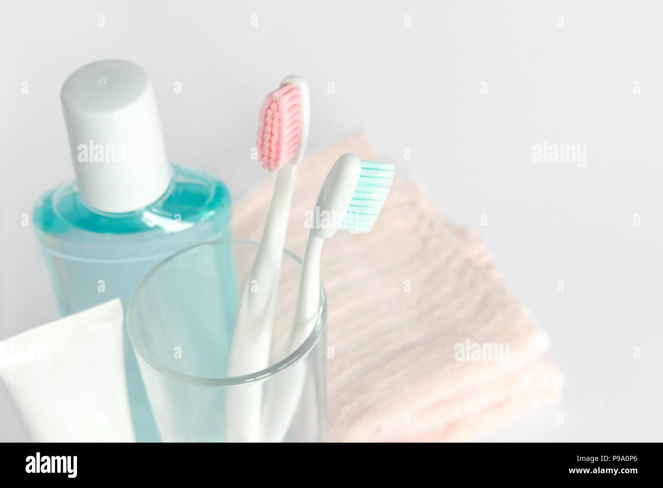 Gli spazzolini da denti, dentifricio, sciacquare e asciugamani su sfondo bianco. Dentale e concetto di assistenza sanitaria. Copia gratuita dello spazio. Foto Stock